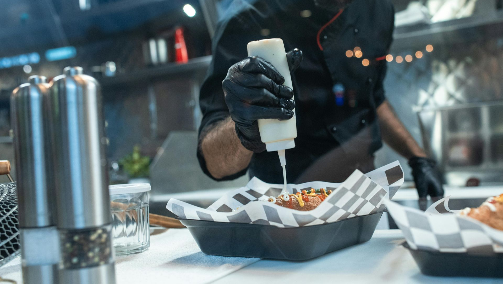 Chef squeezing white sauce onto food in a food truck.