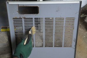 A person is cleaning an air conditioner with a brush.