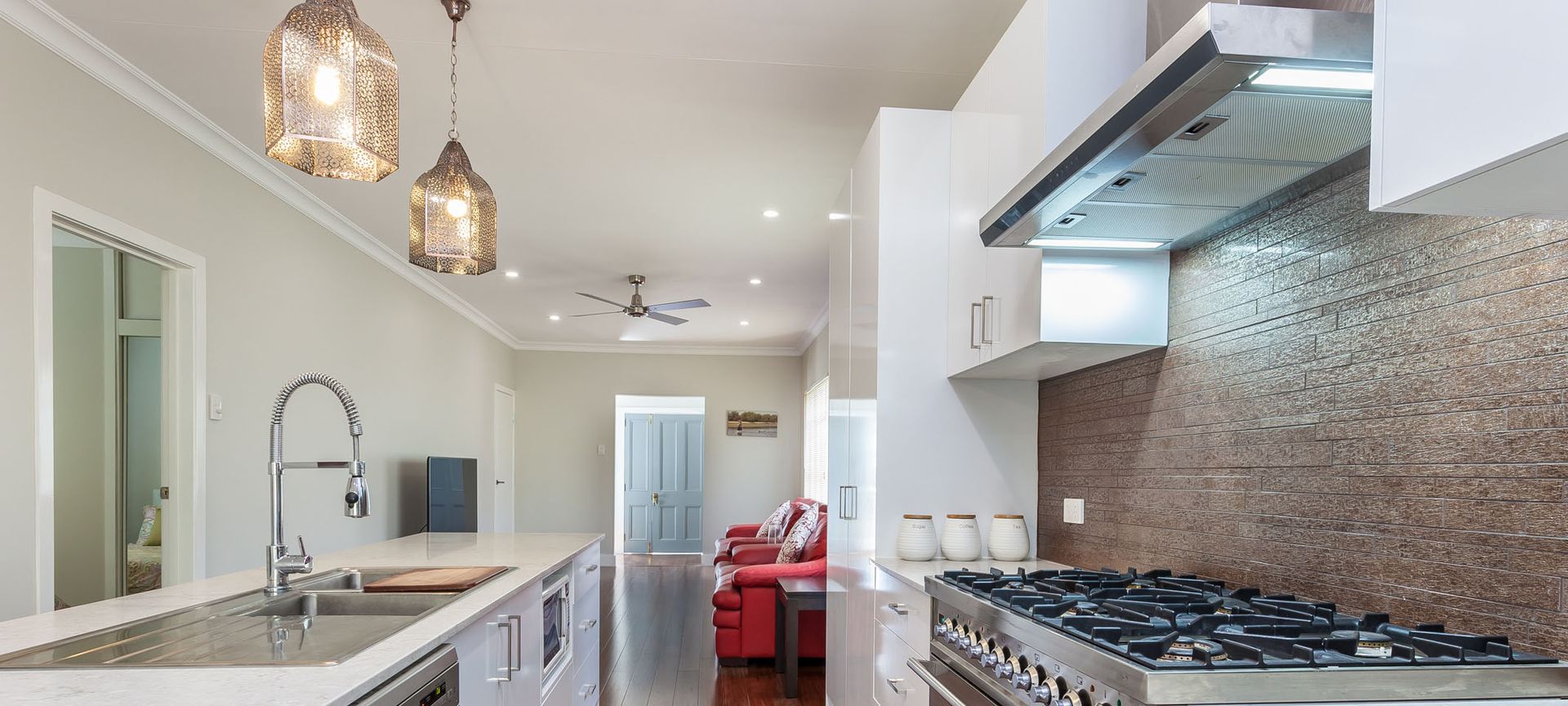 Bright, modern kitchen featuring a long island, stainless steel appliances, and pendant lights.