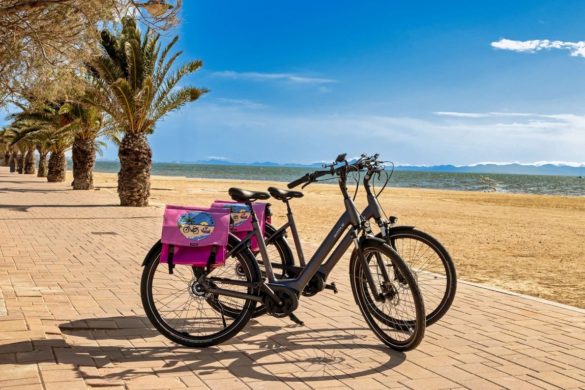 Twee fietsen staan ​​geparkeerd op een stoep naast het strand.