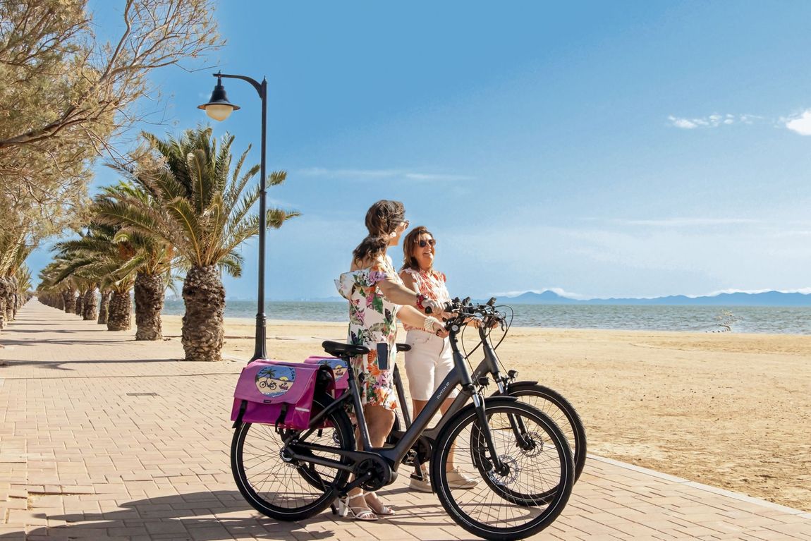 Een man en een vrouw staan ​​naast twee fietsen op het strand.