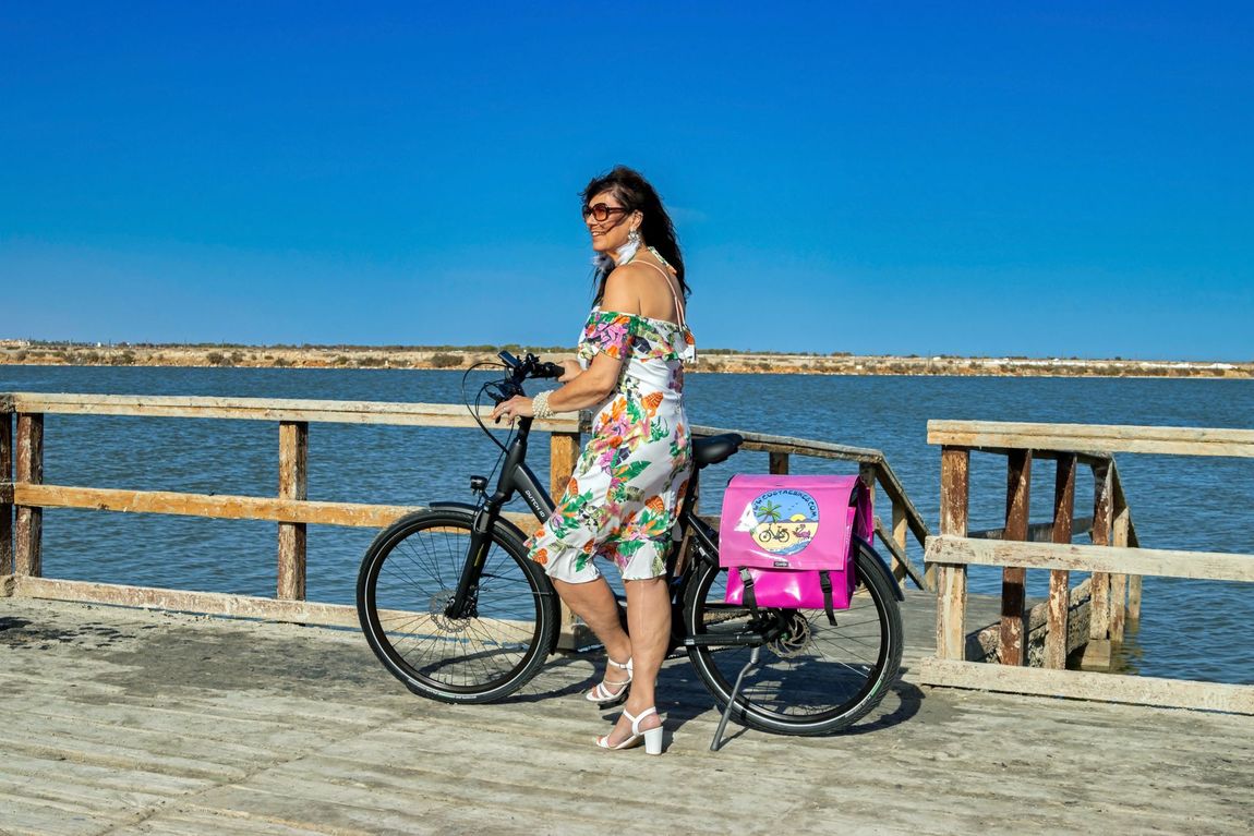 Een vrouw staat naast een fiets op een pier.