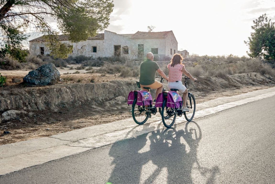 Een man en een vrouw fietsen over een weg.