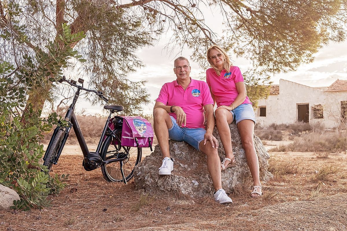 Een man en een vrouw zitten op een rots naast een fiets.