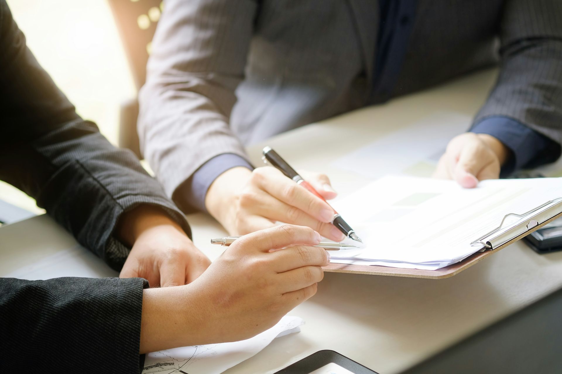 Two people signing a document on a clipboard.
