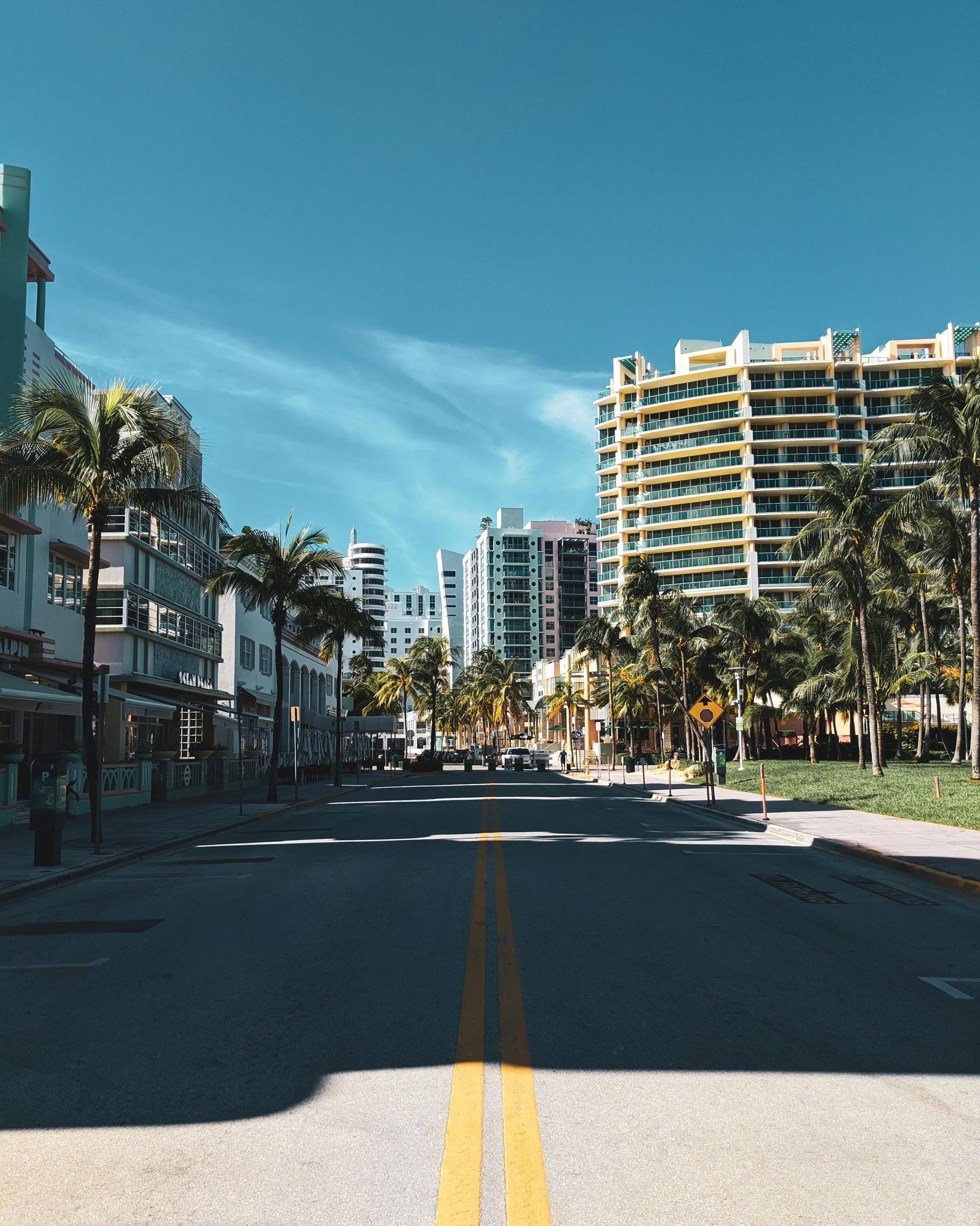 Aerial view of Miami Beach, Florida, with turquoise ocean, sandy beach, and white buildings under a blue sky.