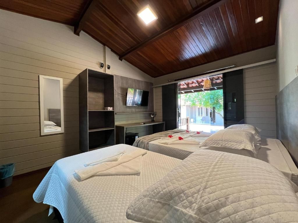 Um quarto de hotel com duas camas, um espelho e uma televisão.