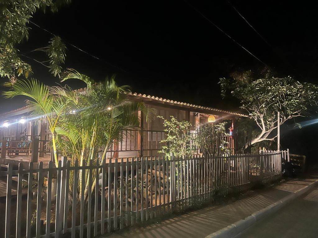 Uma casa com uma cerca ao redor é iluminada à noite.