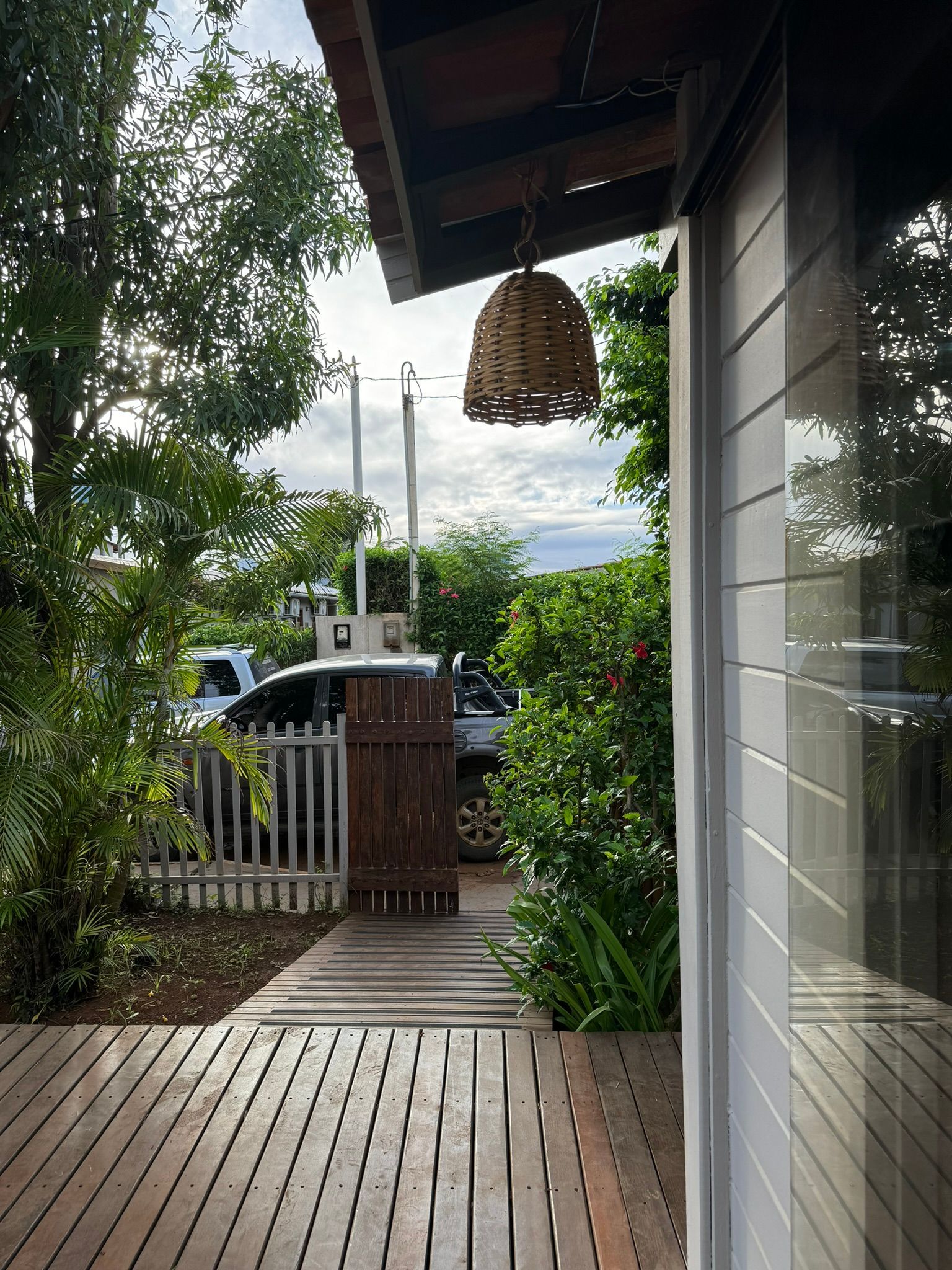 Um deck de madeira que leva a uma casa com um carro estacionado na frente.