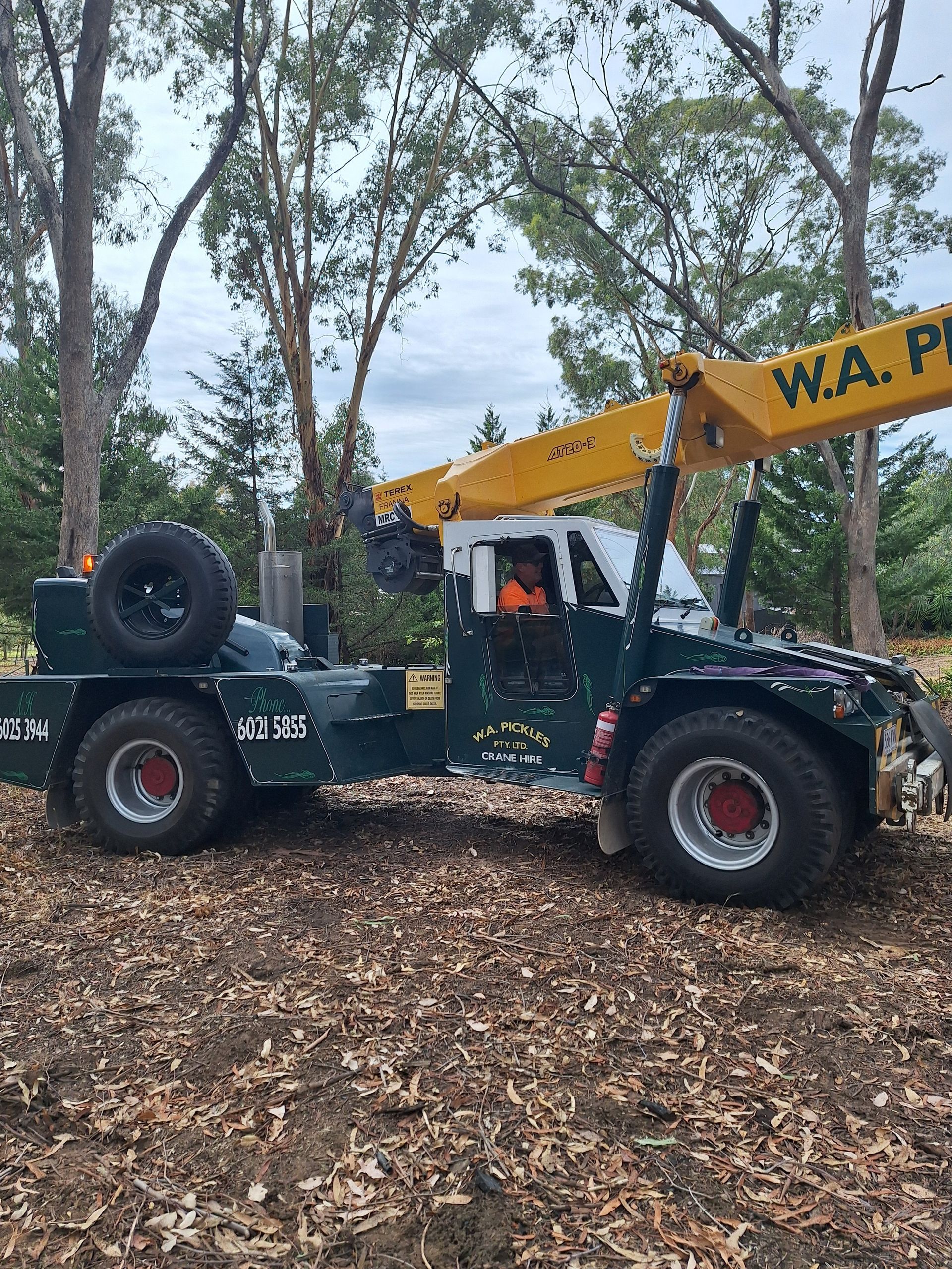 Yellow W.A. P. telehandler parked on a leafy forest floor with a spare tire on the rear