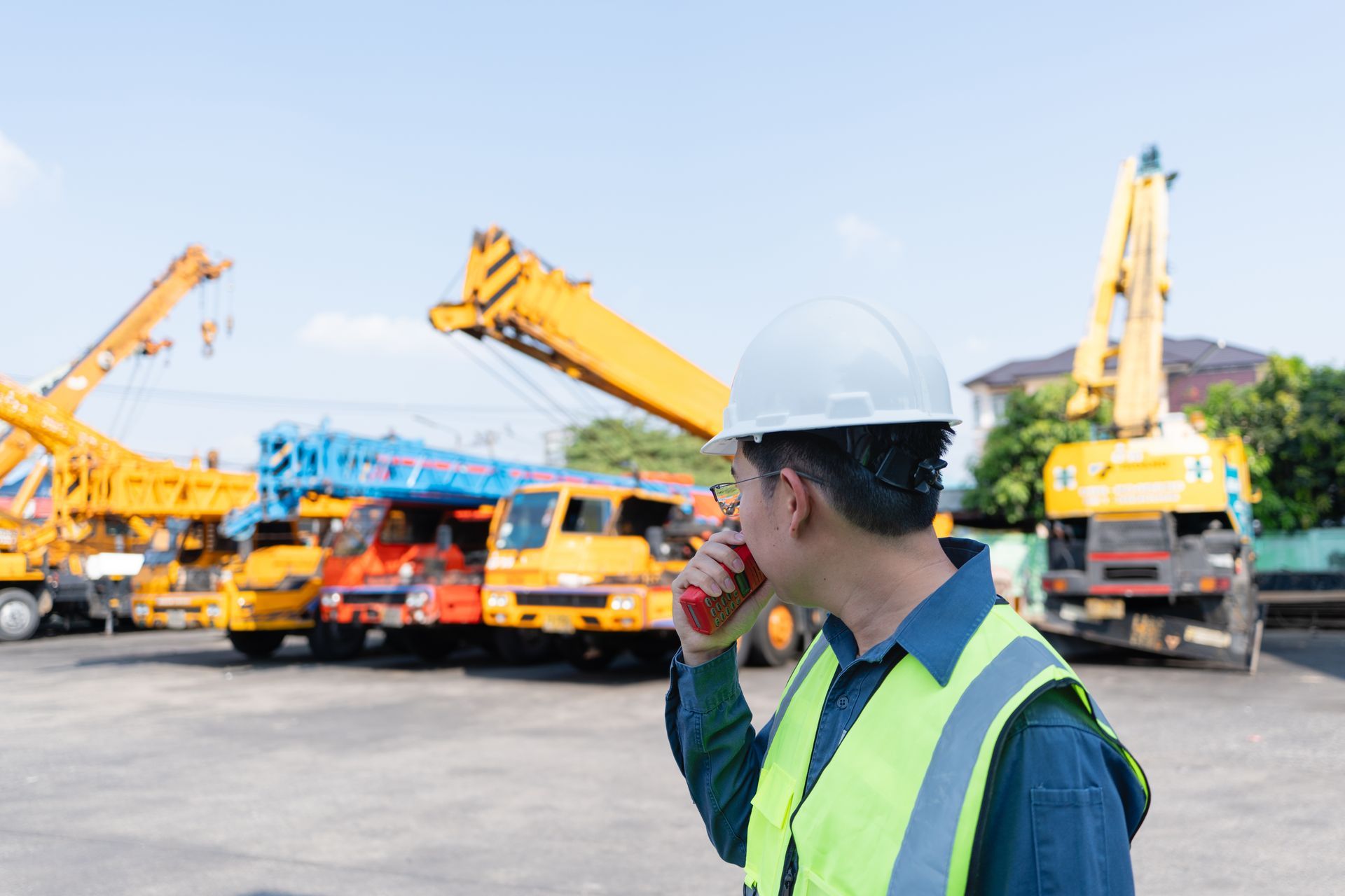 AN ENGINEER USES A RADIO BESIDES MOBILE CRANES AT A HEAVY EQUIPMENT YARD. AN ENGINEER USES A RADIO BESIDES MOBILE CRANES AT A HEAVY EQUIPMENT YARD.