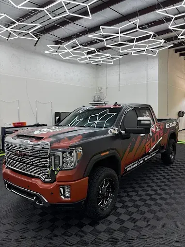 GMC truck with custom wrap in a well-lit shop, black wheels.