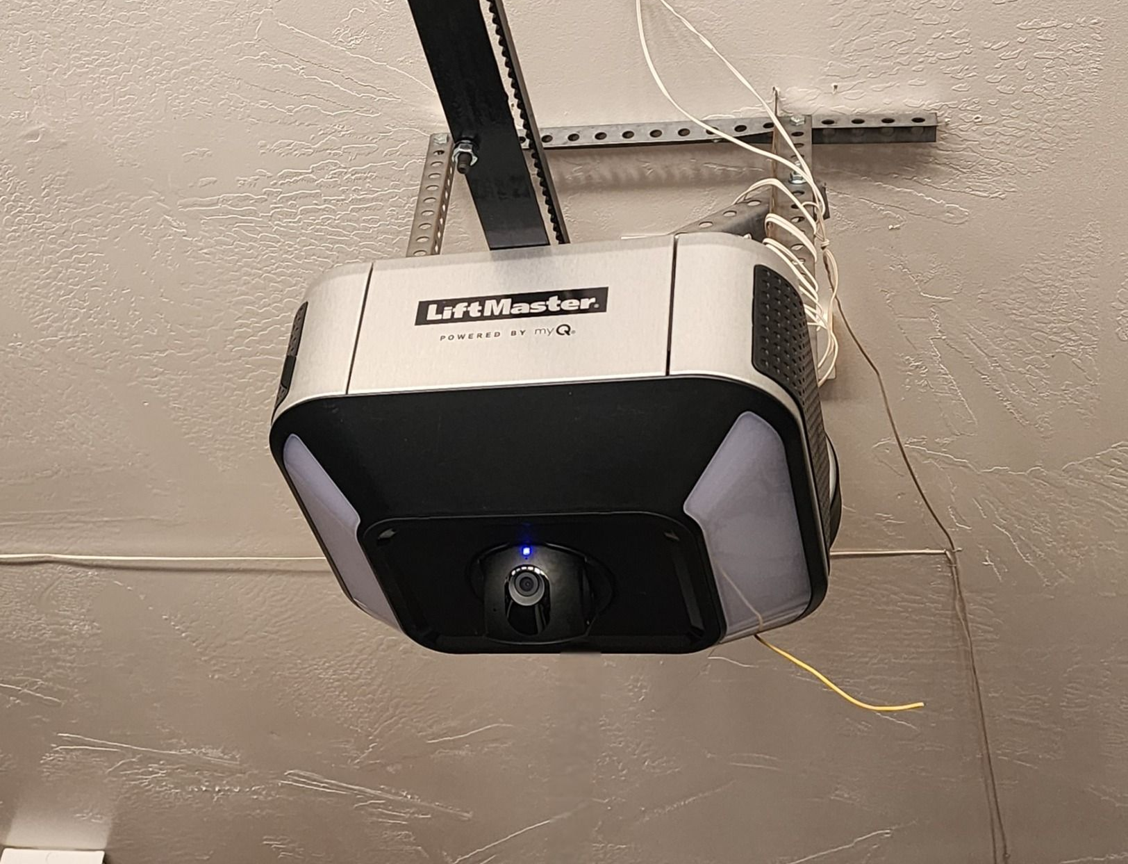 Garage door opener mounted on ceiling, light on.