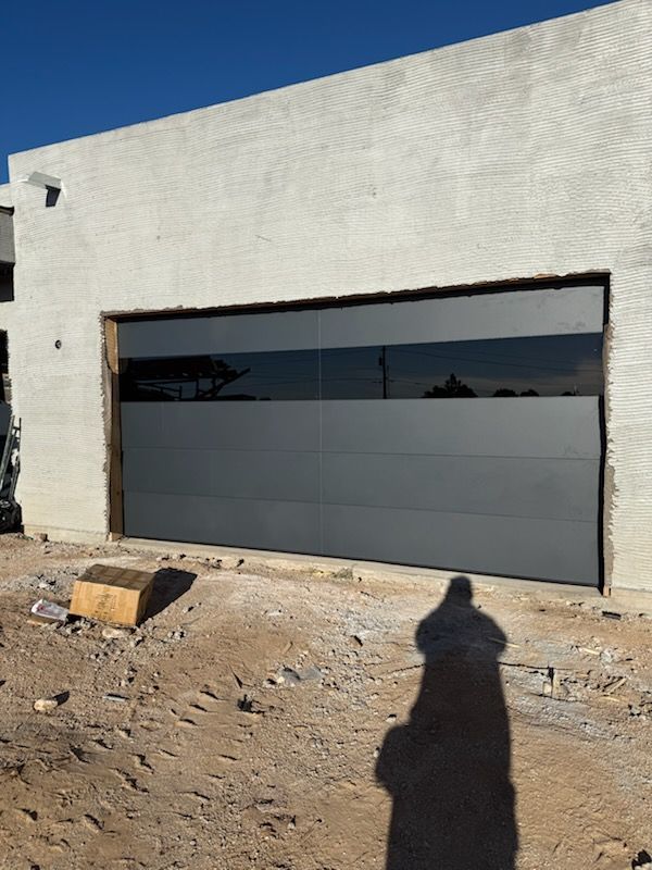 Gray garage door with tinted window panel on a building under construction.