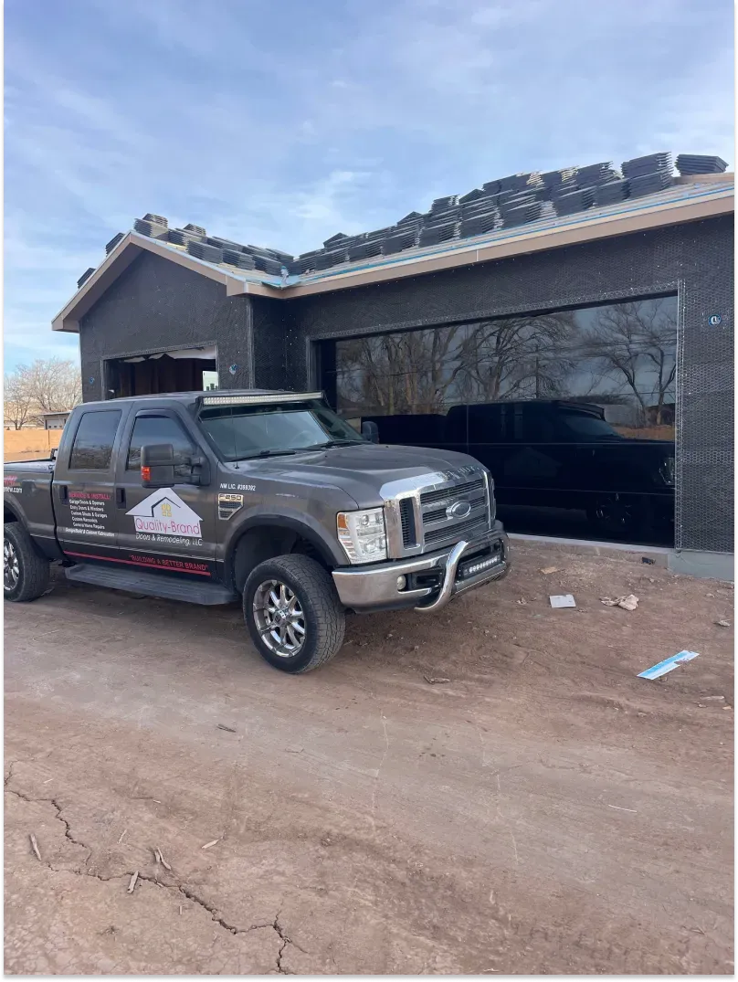 Gray pickup truck parked near a dark garage under construction.