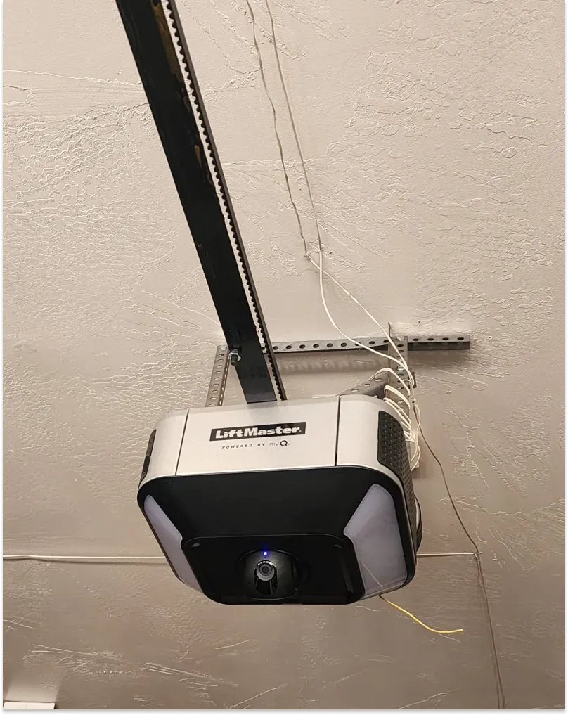 Garage door opener mounted on a white ceiling; LiftMaster model visible with camera and lights.