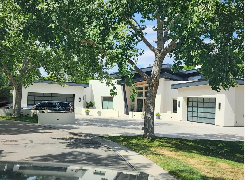 Exterior view of a building with two modern garage doors with horizontal glass panels. Scaffolding visible above.
