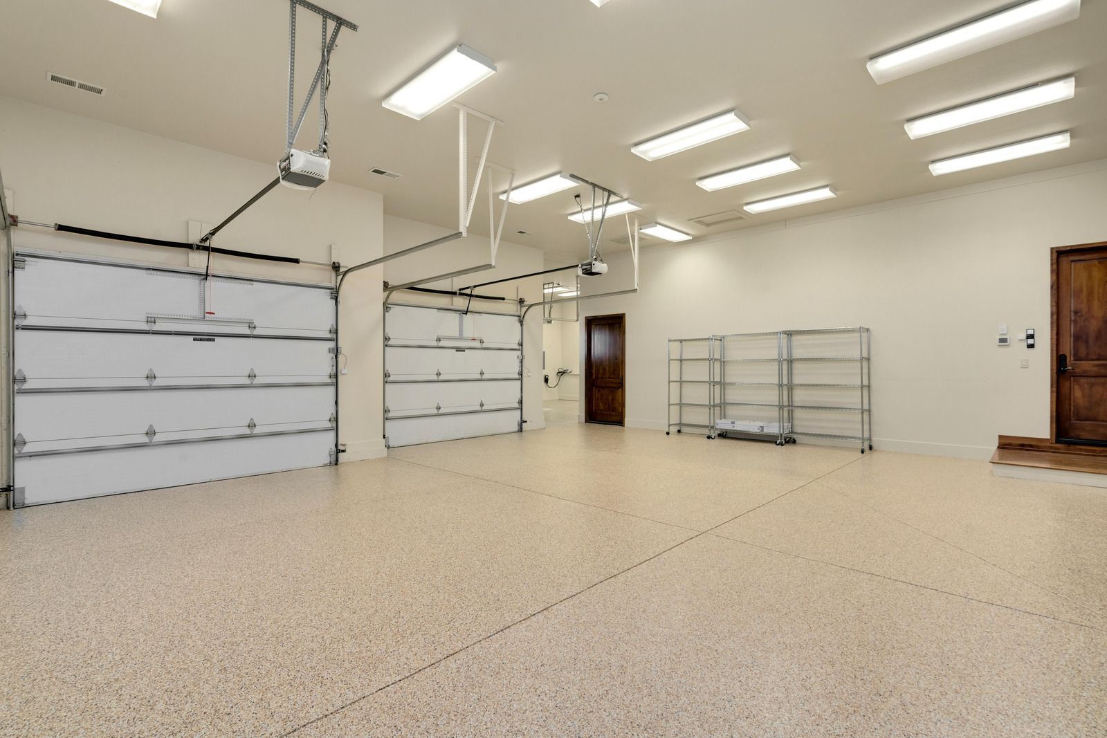 Tan garage door on a house with a small trailer parked in front. Blue sky.