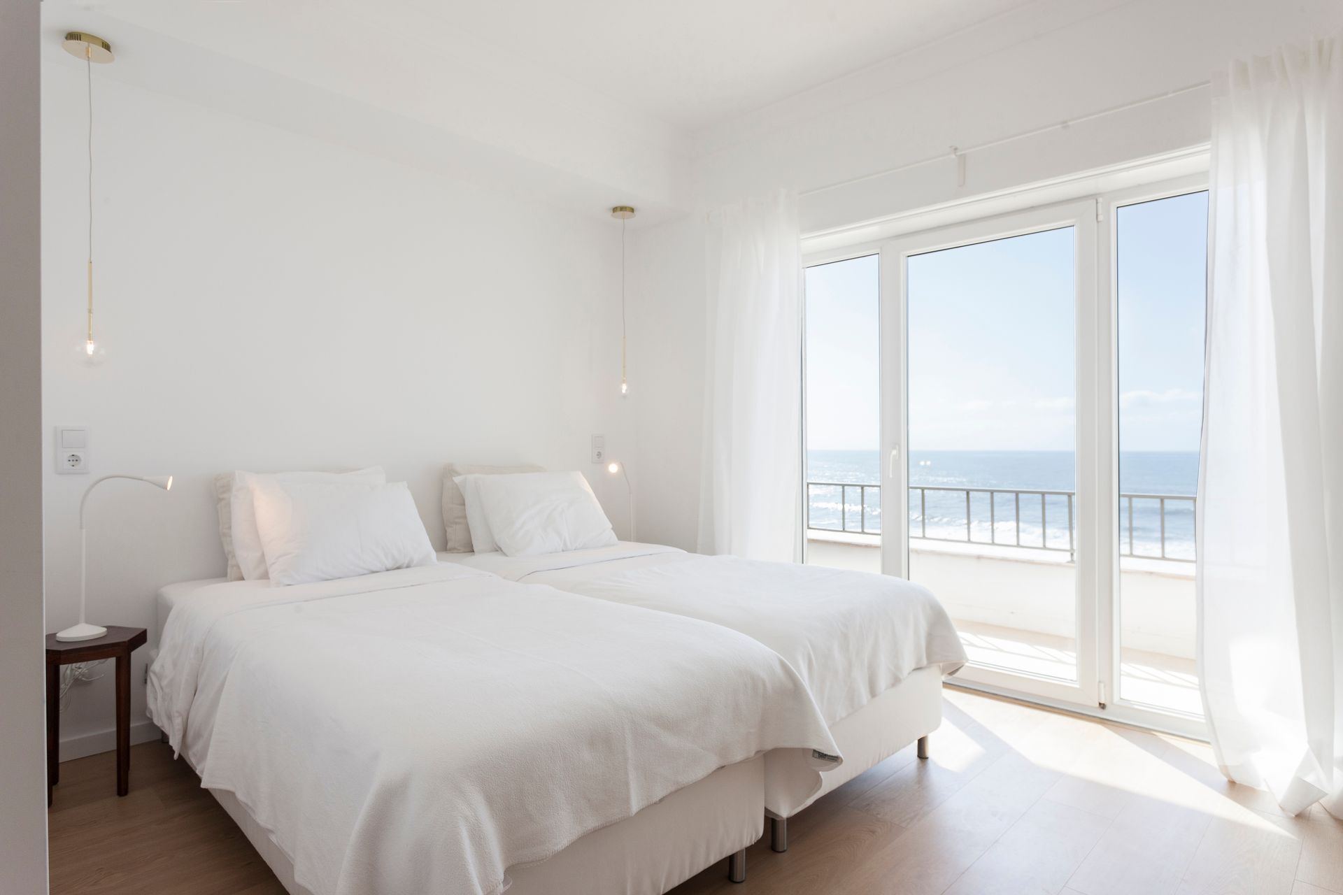 a bedroom with two beds and a large window overlooking the ocean .