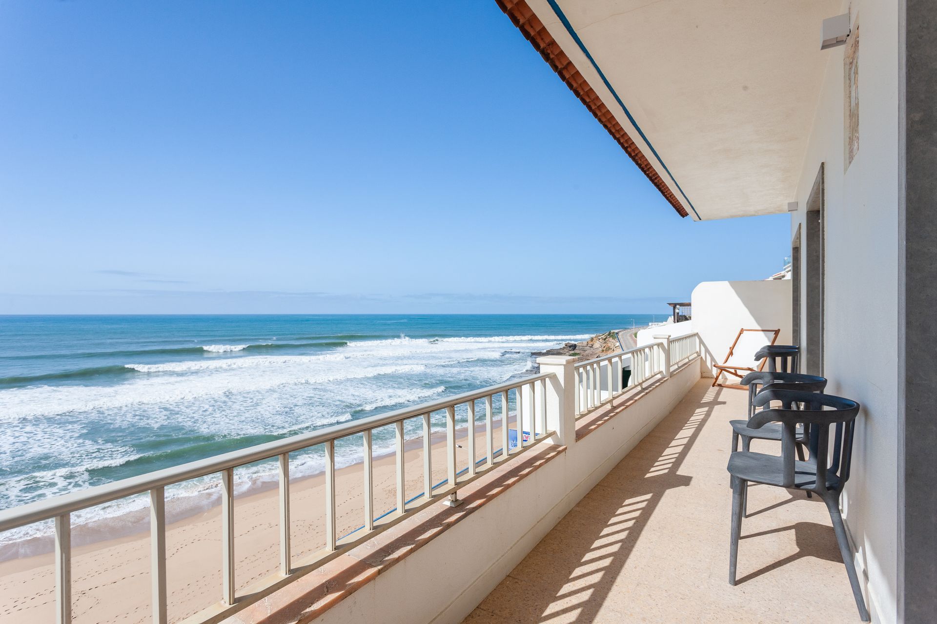a balcony overlooking the ocean with chairs and a railing