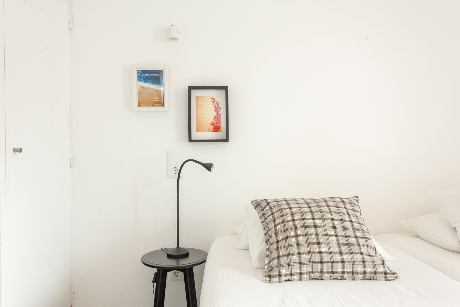 a bedroom with a bed , nightstand , lamp and paintings on the wall .