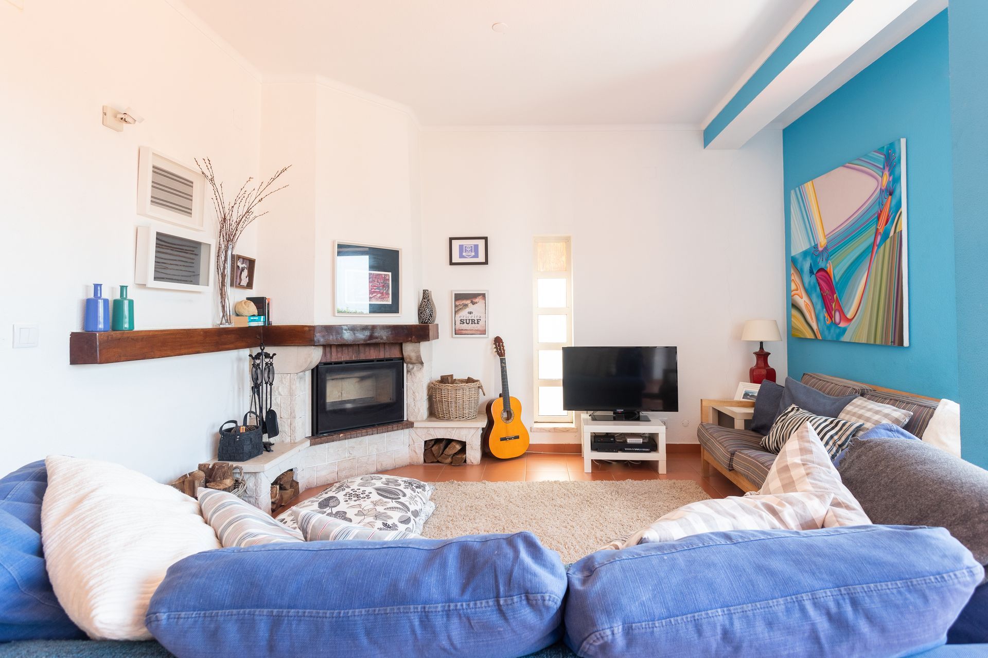 a living room with a blue couch , fireplace , television and guitar .