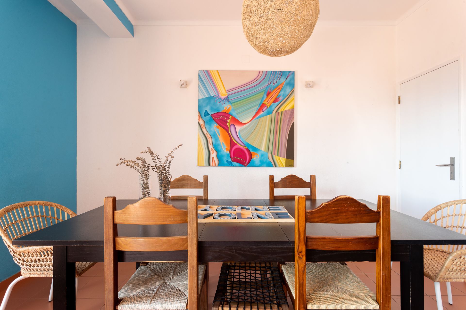 a dining room with a table and chairs and a painting on the wall .