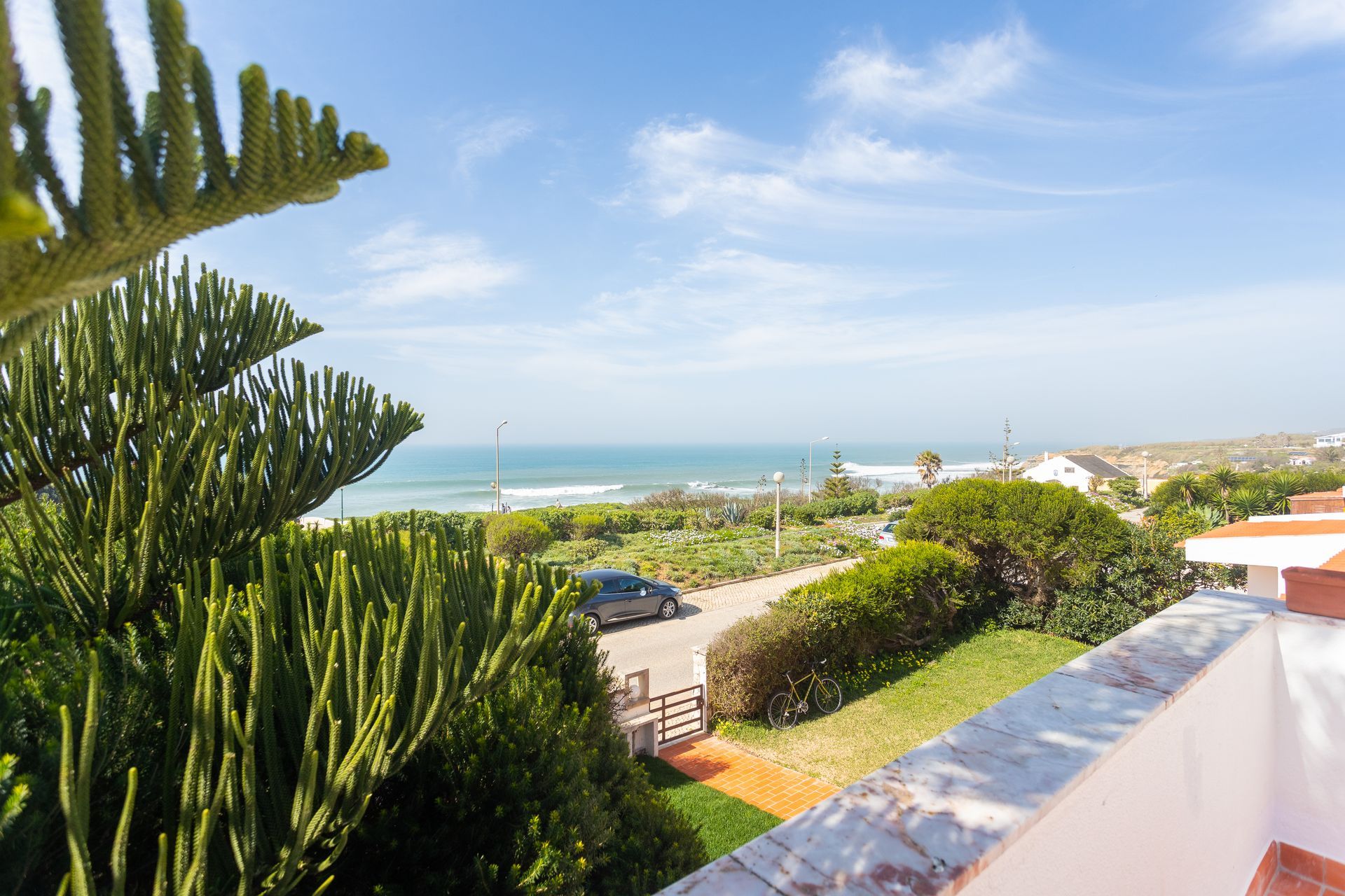 a view of the ocean from a balcony with trees in the foreground