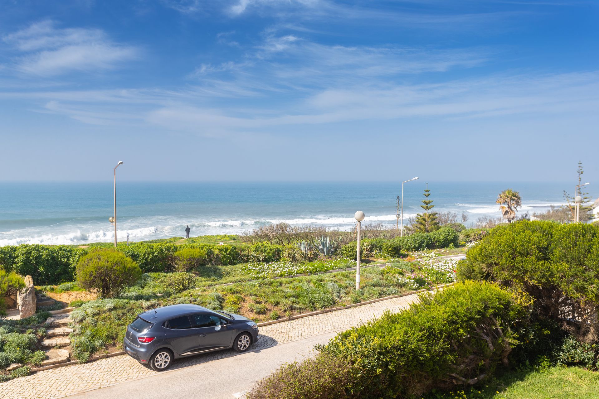 a car is parked on the side of a road next to the ocean .