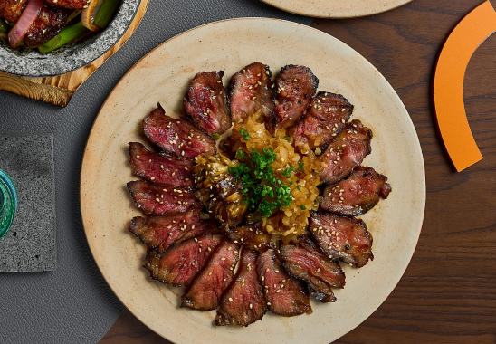 A plate of meat and rice on a wooden table.