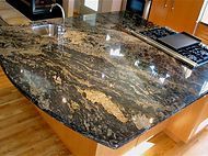 A kitchen with a granite counter top , sink and stove.