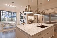 A kitchen with a large island , sink , refrigerator and stainless steel appliances.