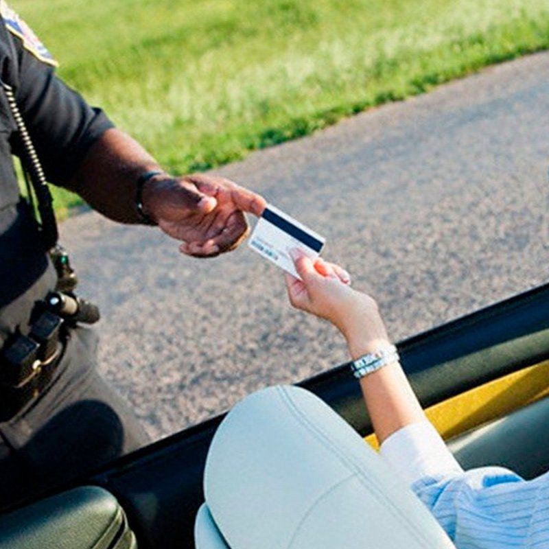 A police officer is checking an ID of a driver.