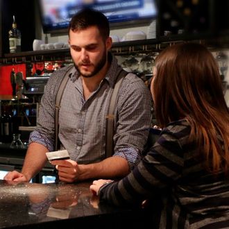 A bartender is checking an ID at a bar or restaurant.