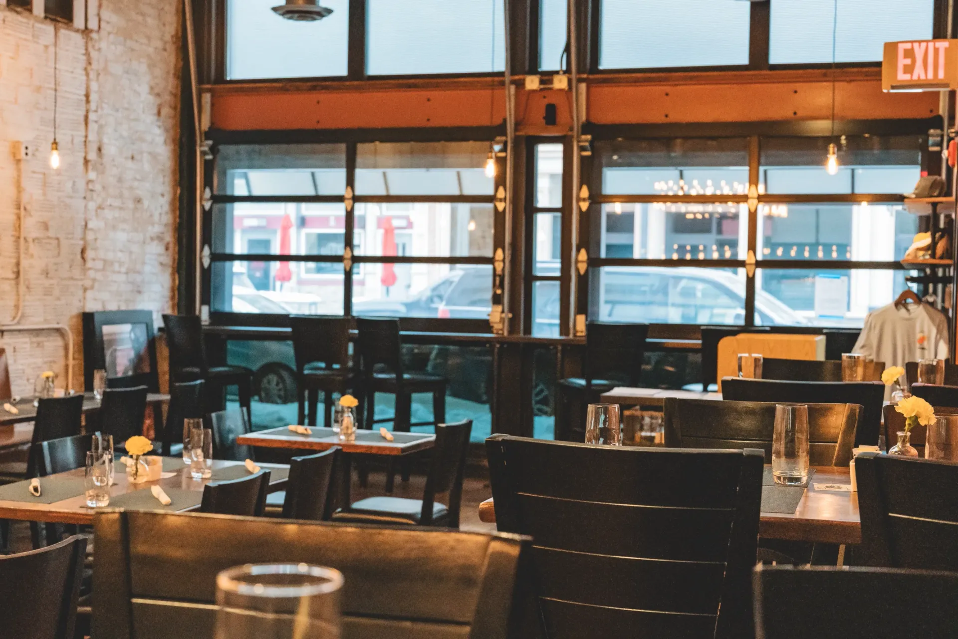 Restaurant interior with tables set for dining, visible through large windows.