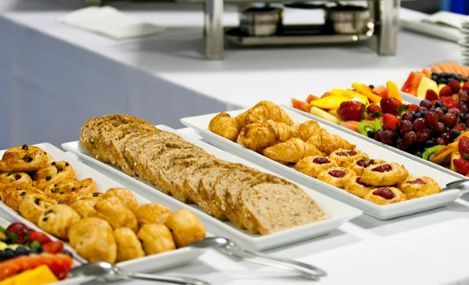 Buffet table with bread, pastries, and fruit.