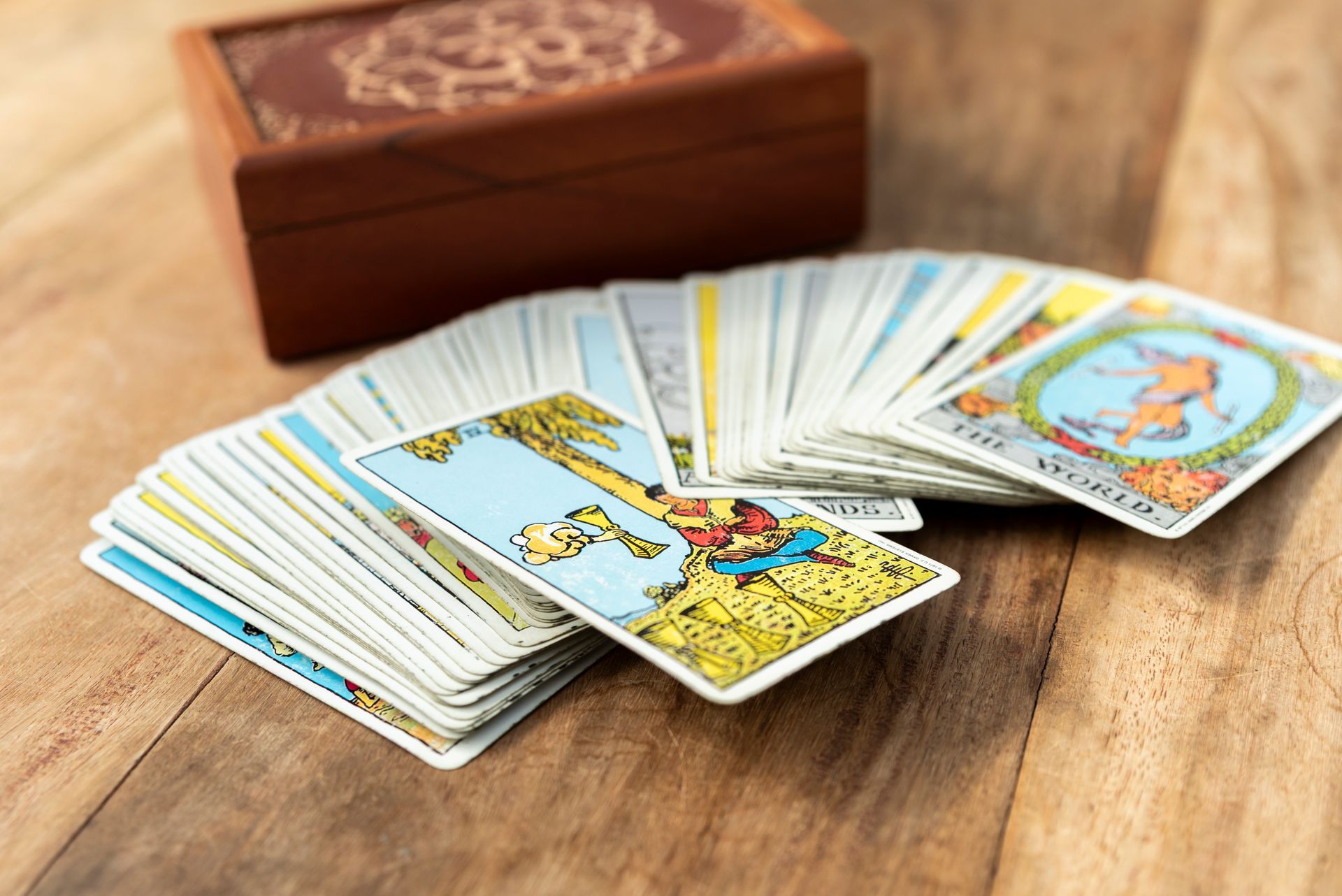 Een tarotkaartendeck uitgespreid op een houten ondergrond, met een houten doos op de achtergrond.