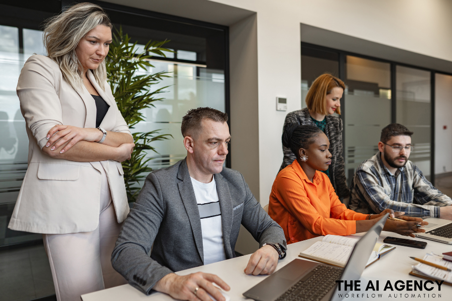 A group of people are sitting at a table looking at a laptop computer.