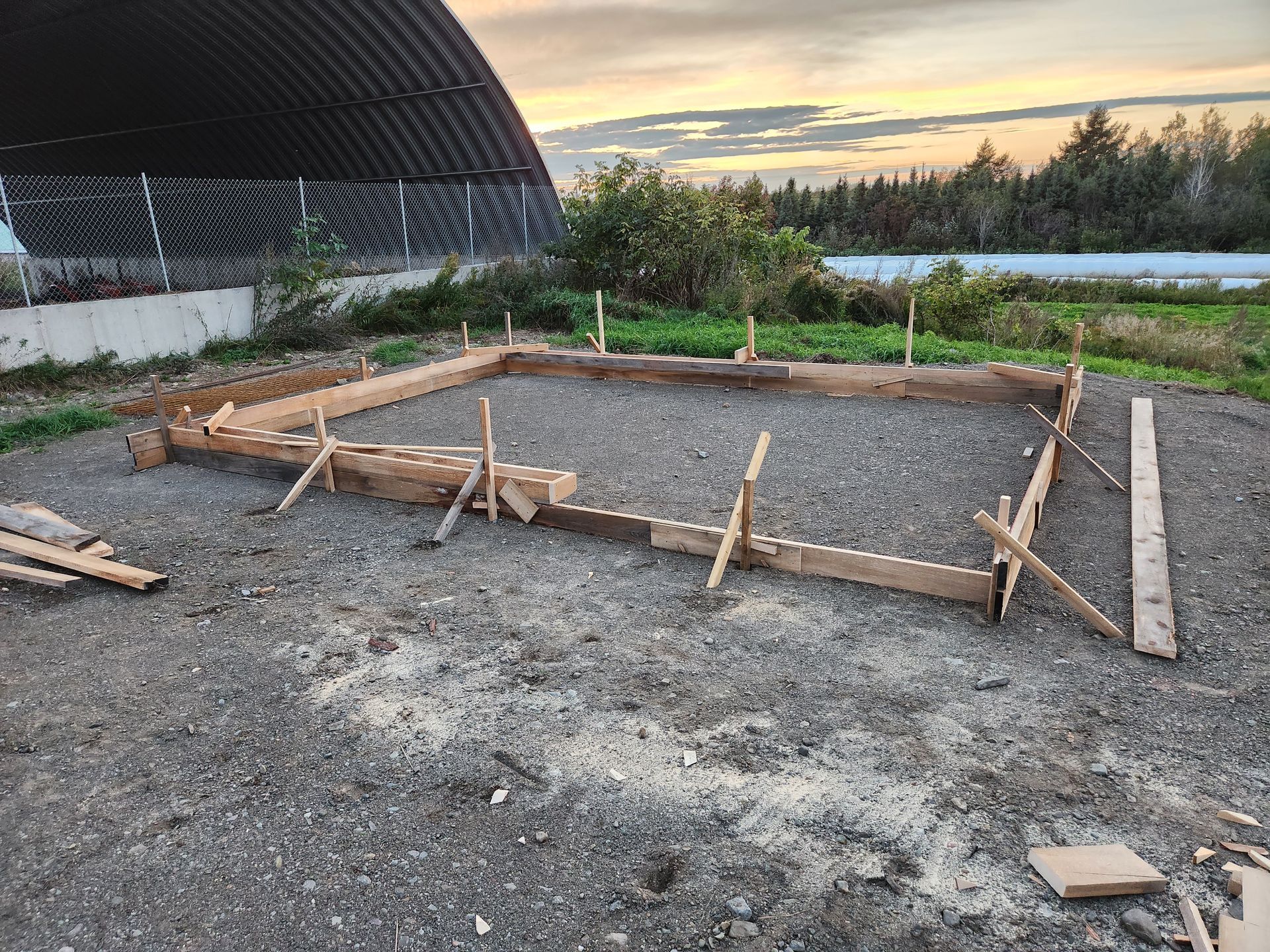 Une fondation en béton est en cours de construction dans une zone de gravier.