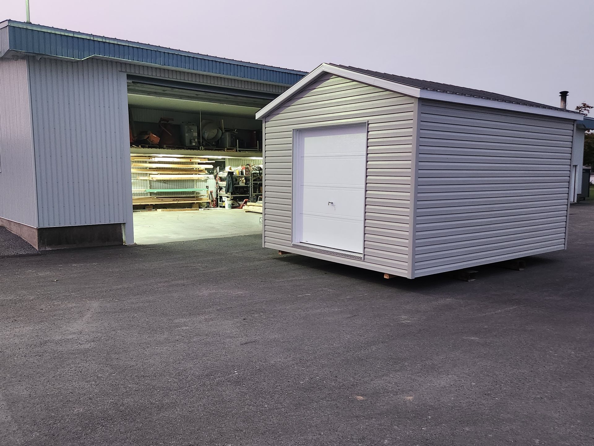 Un hangar avec une porte blanche se trouve devant un bâtiment.