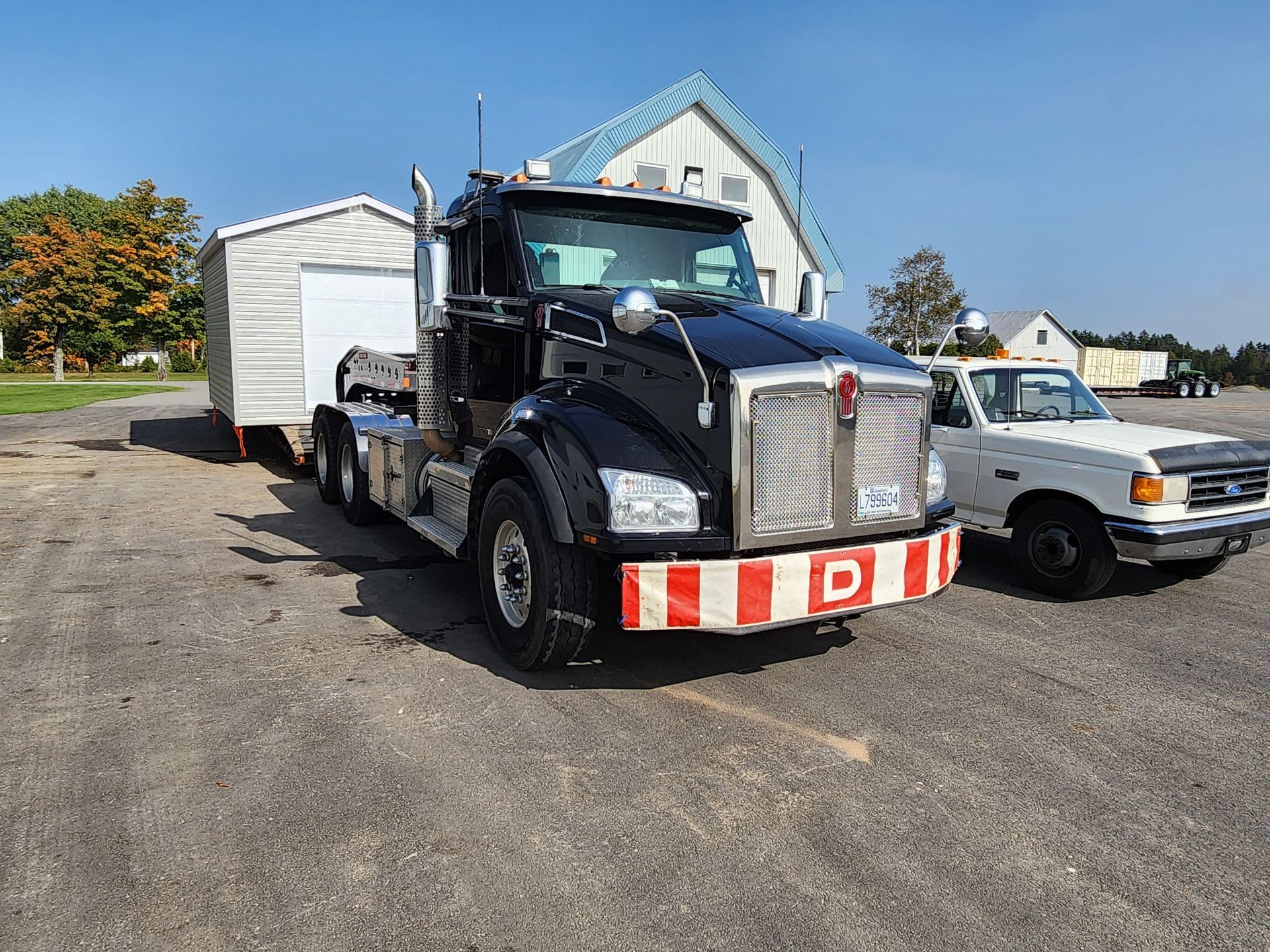 Un semi-remorque noir est garé à côté d'un camion blanc sur un parking.