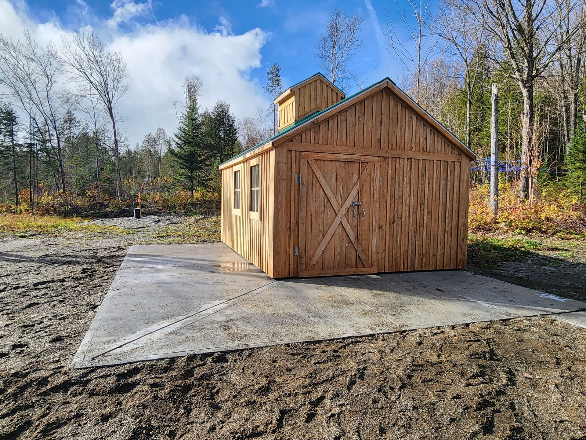 Un hangar en bois se trouve au milieu d'un champ de terre.