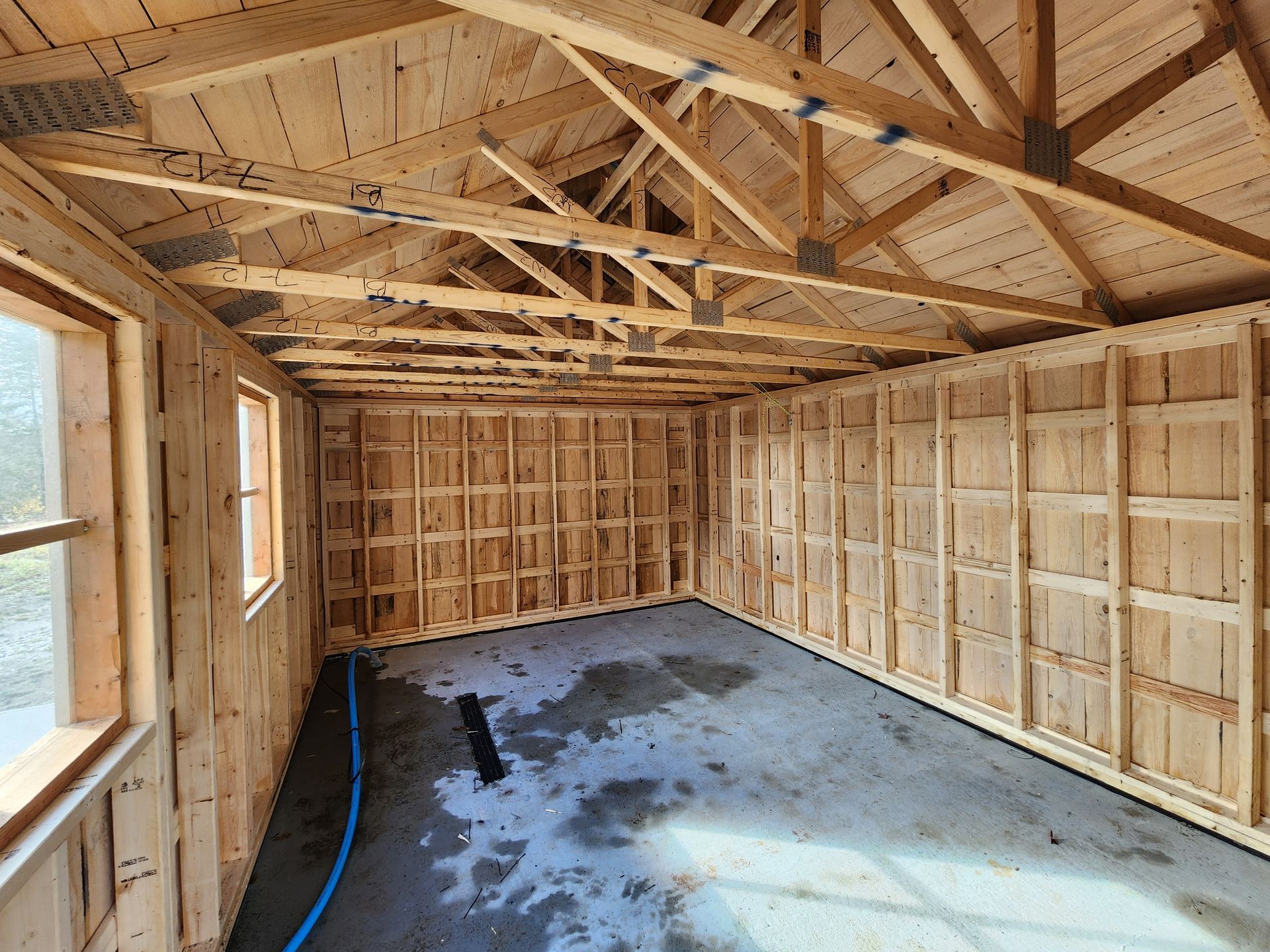 L'intérieur d'un bâtiment en bois en construction avec un tuyau bleu au milieu de la pièce.