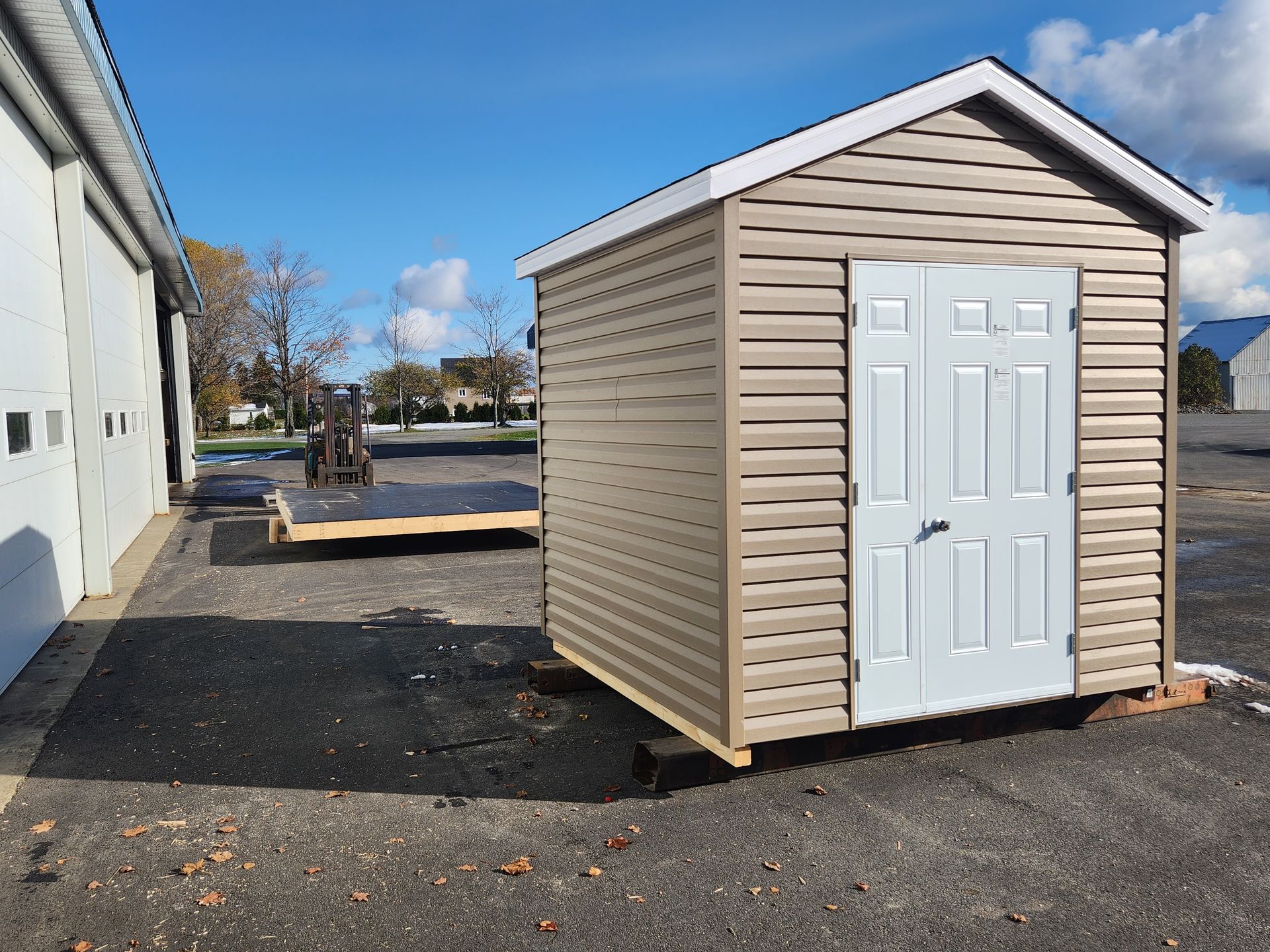 Un petit hangar avec une porte blanche se trouve dans un parking.
