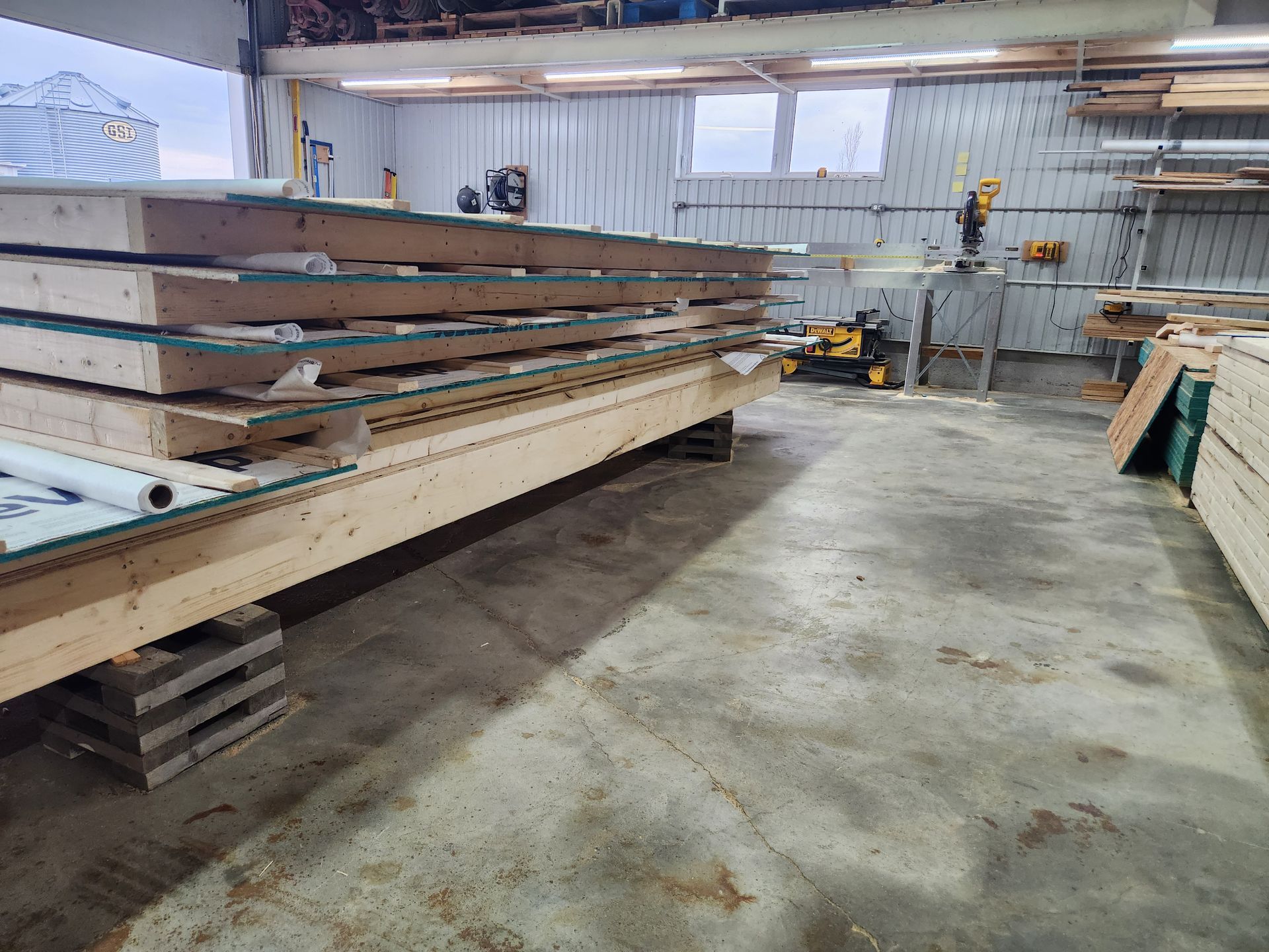 Un entrepôt rempli de palettes en bois et d'une scie circulaire.