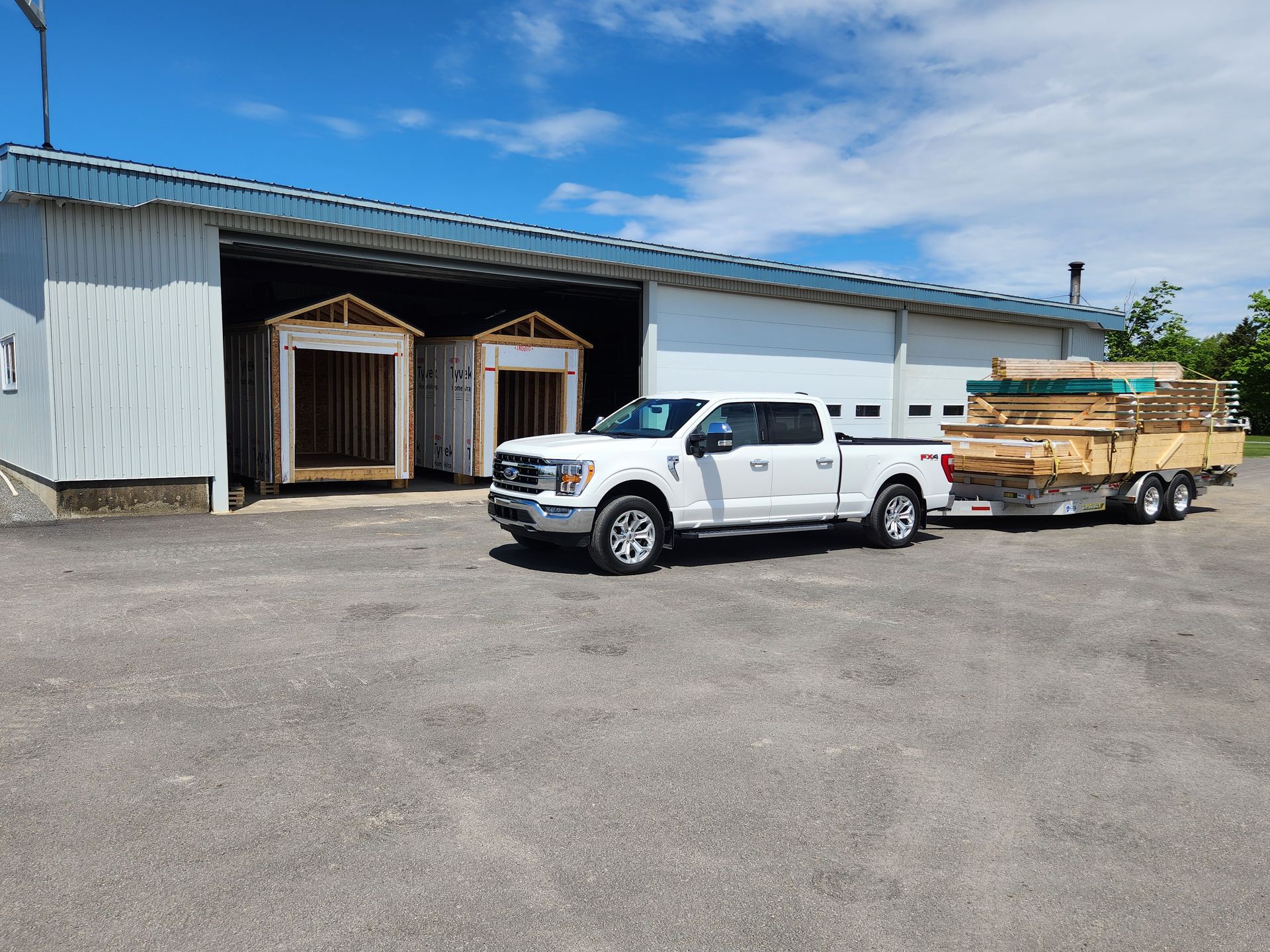 Un camion blanc avec une remorque est garé devant un bâtiment.