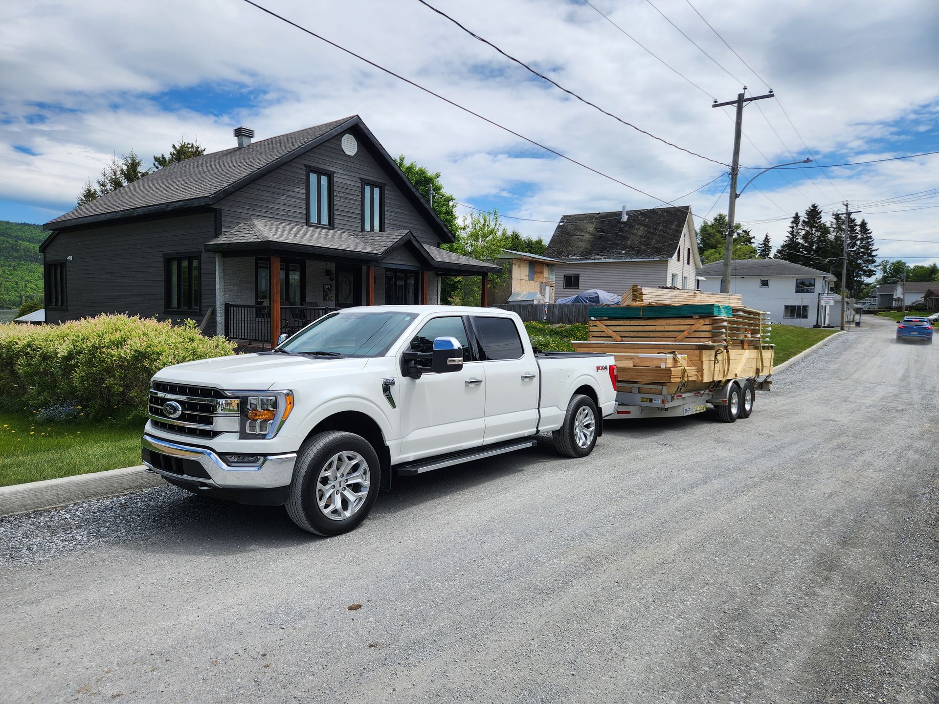 Un camion blanc tire une remorque pleine de bois.
