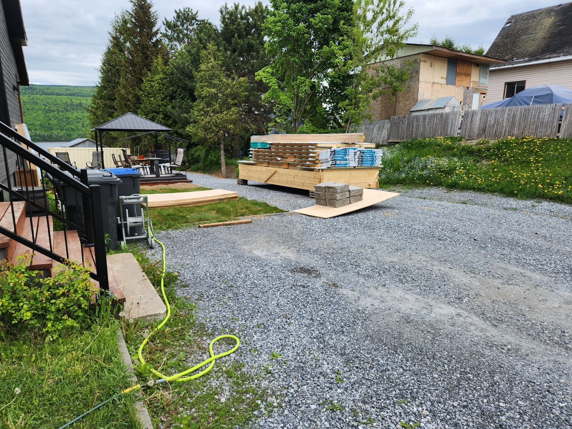 Une allée de gravier menant à une maison avec un tuyau attaché.