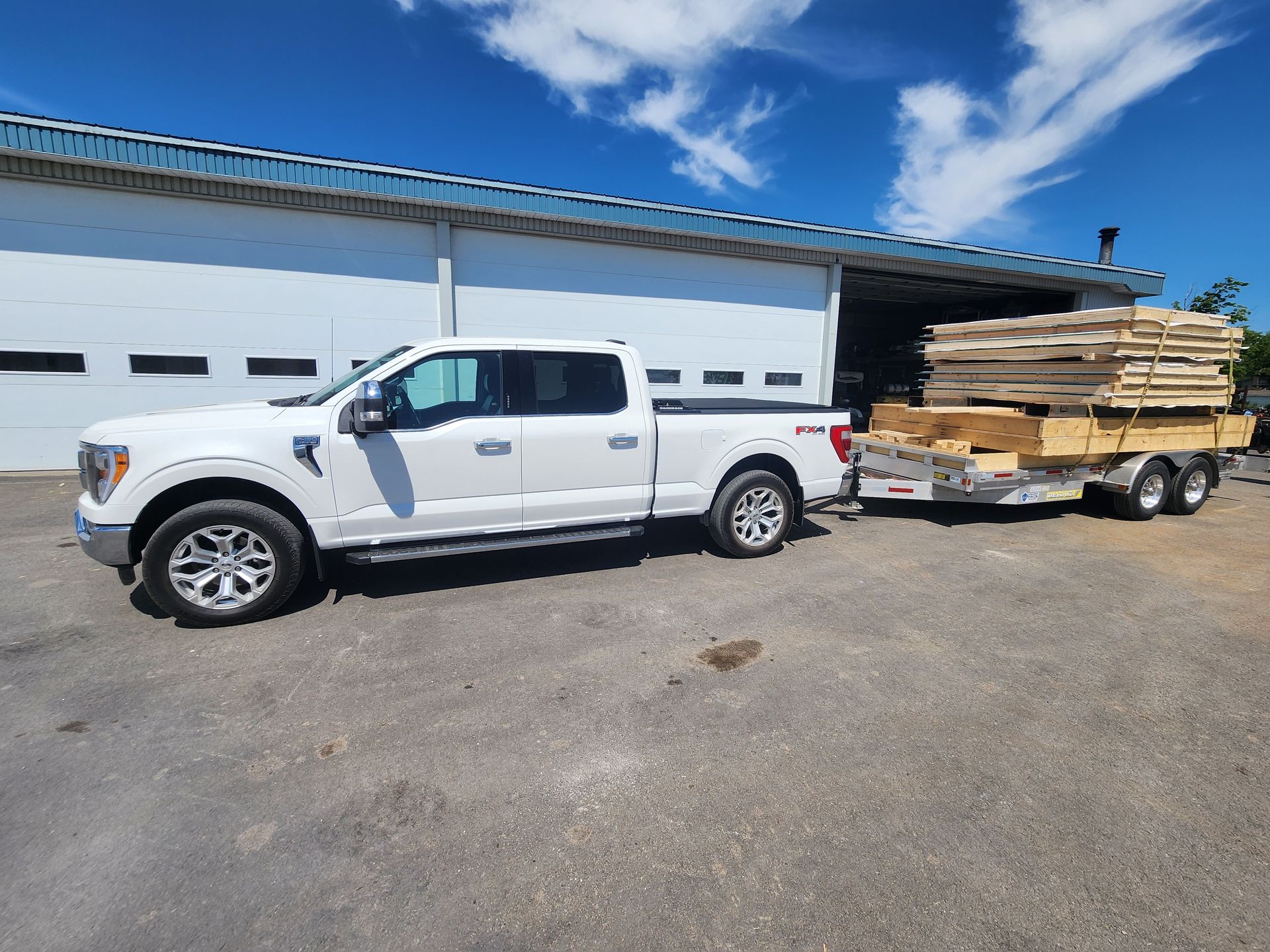 Un camion blanc tire une remorque pleine de bois.