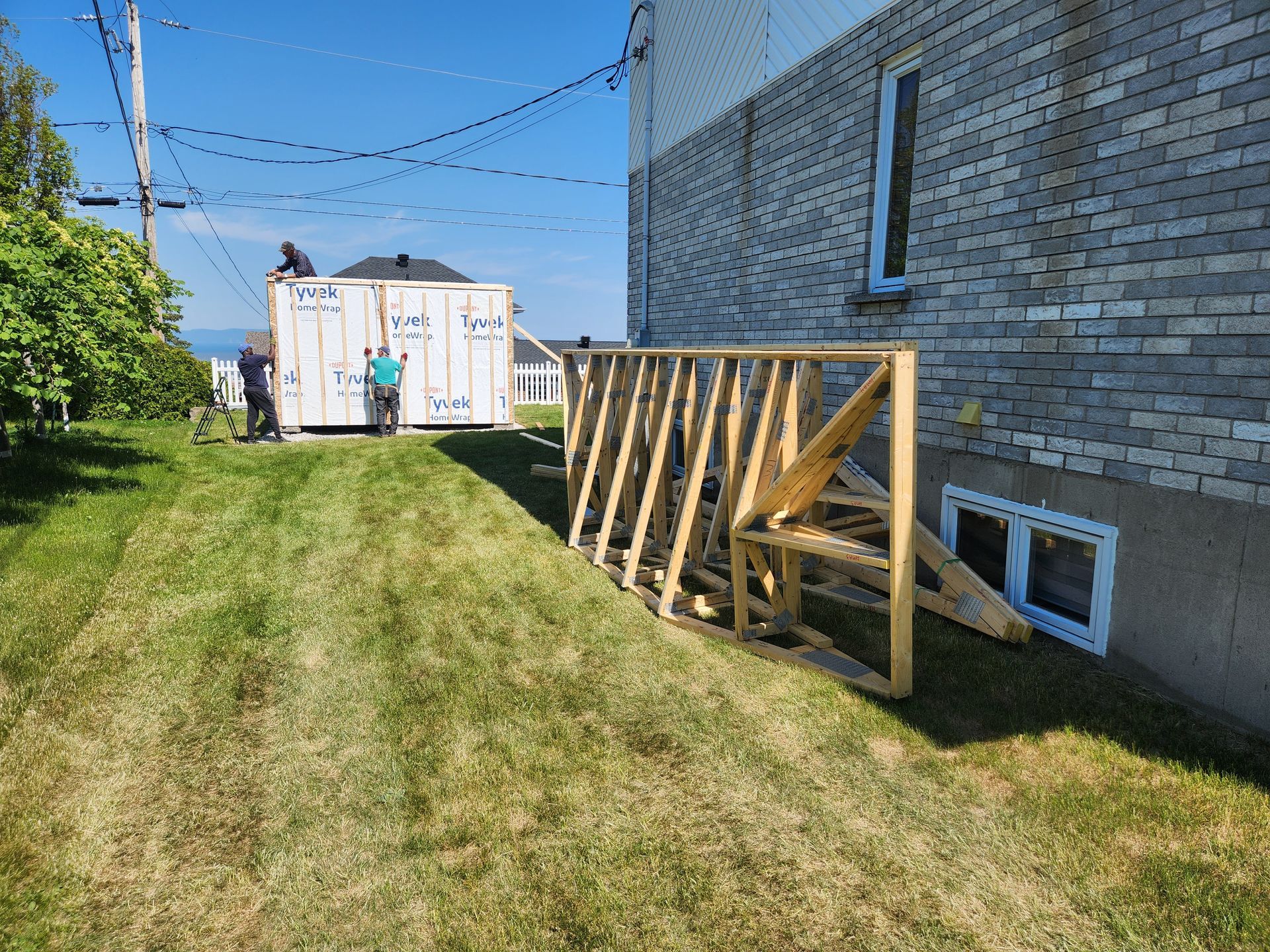Une clôture en bois est en train d'être construite devant un bâtiment en briques.